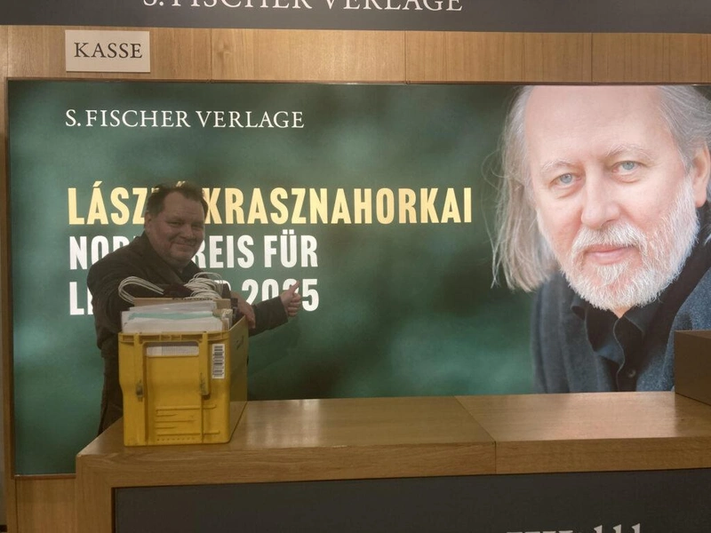 Plakát Krasznahorkai Lászlóról a Frankfurti Nemzetközi Könyvvásáron a német kiadója standjánál (a fotón a cikk szerzője, Zarándy Zoltán)